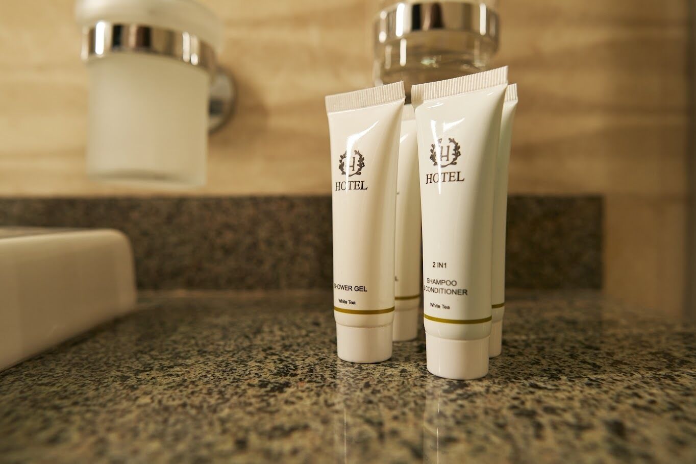 Deux tubes de produits de toilette d’hôtel posés sur un comptoir en granit.