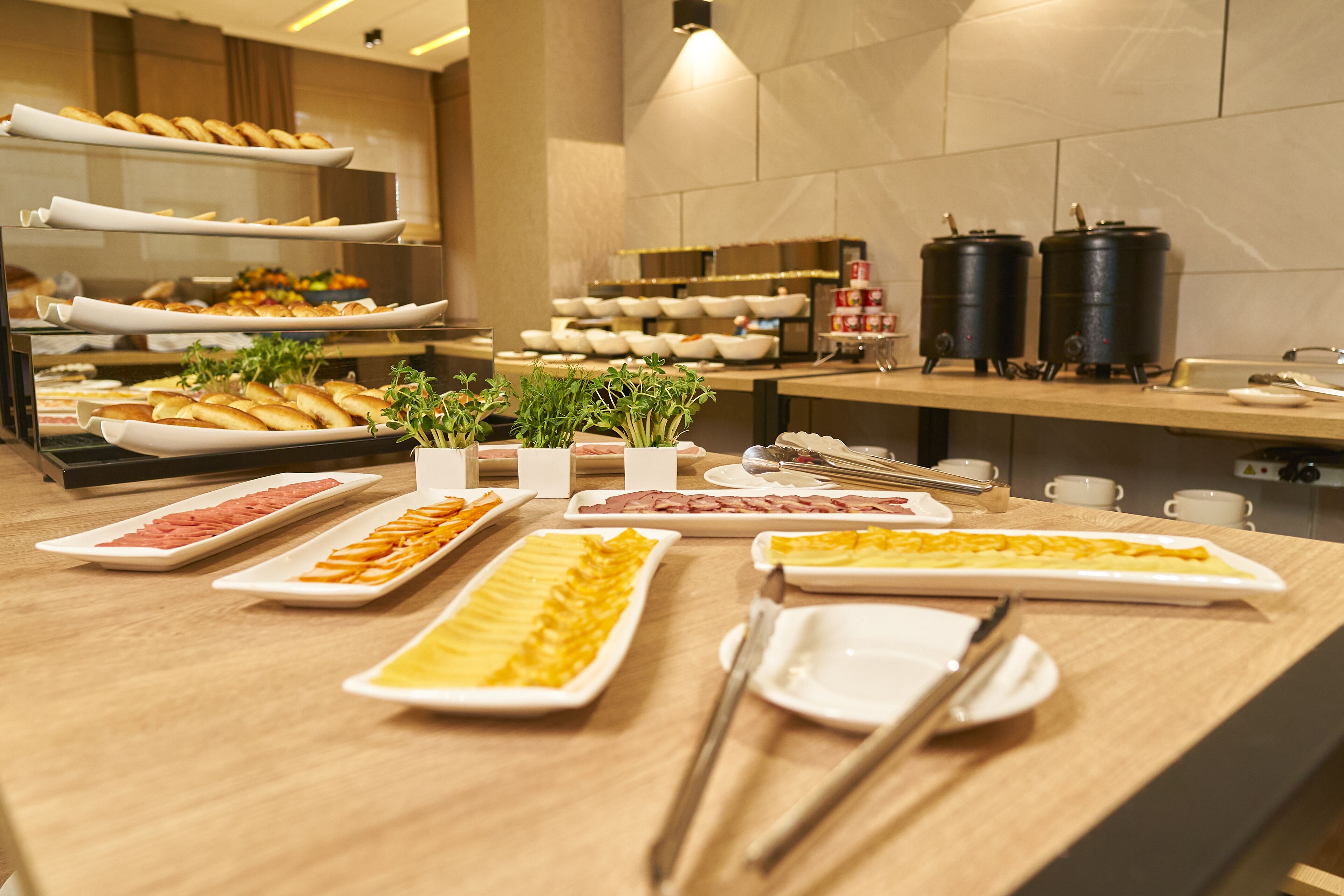 Un buffet proposant divers plats et couverts, le tout disposé sur une table en bois.