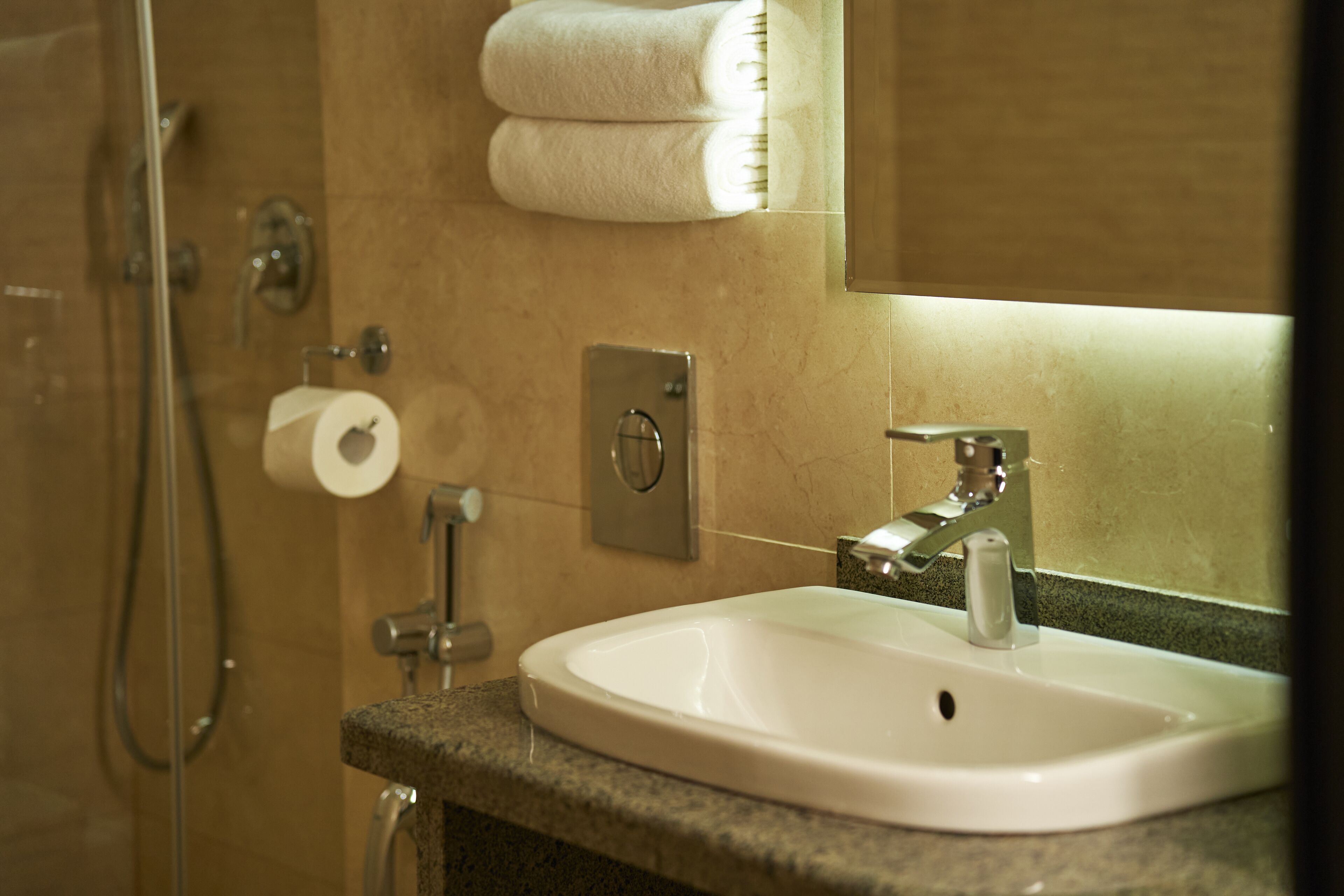 A bathroom with a sink, mirror, towel rack, and shower.