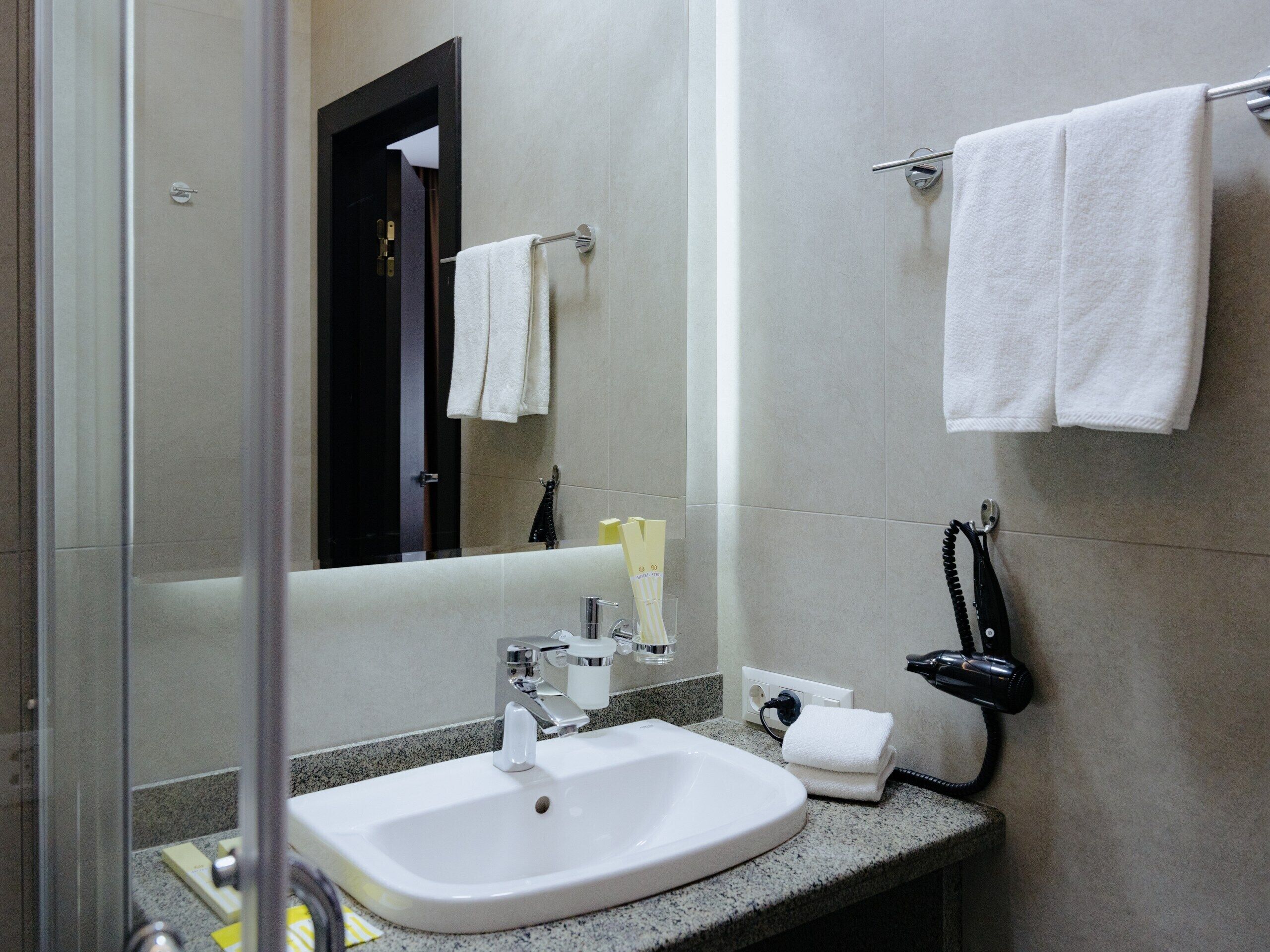 A bathroom with a sink, mirror, towel rack, and hairdryer.