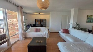 A spacious living area with a large window, a sofa, a coffee table, and a hanging light fixture.