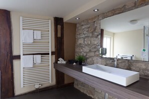 A modern bathroom with a stone accent wall, a large rectangular sink, and a towel rack with multiple towels.