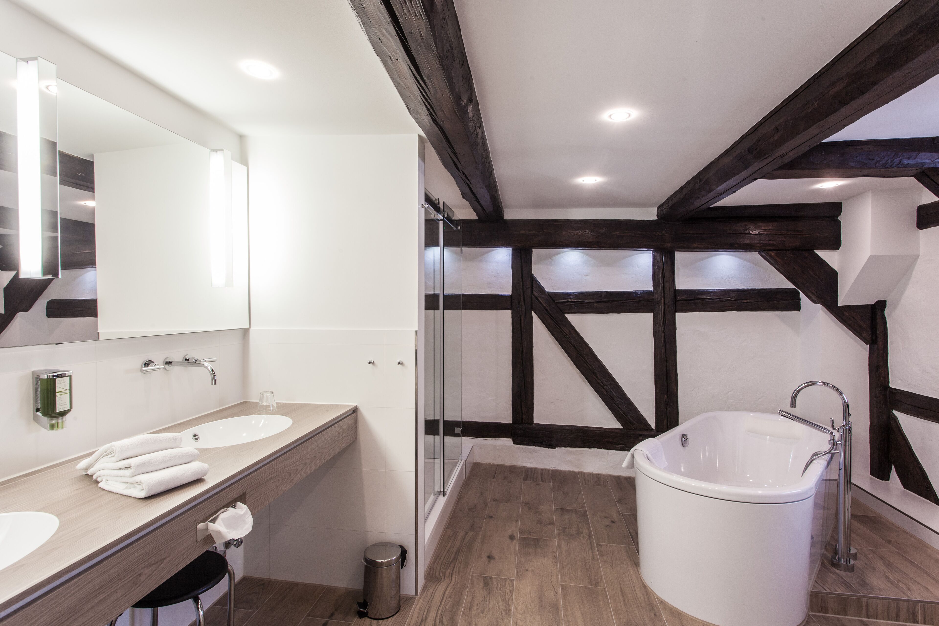 Een moderne badkamer met twee wastafels, een groot bad en een douchecabine met glazen wanden.