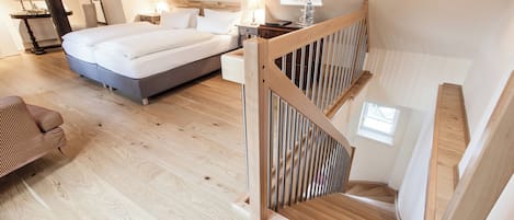 Un dormitorio con una cama grande, una escalera de madera y un escritorio con una silla.