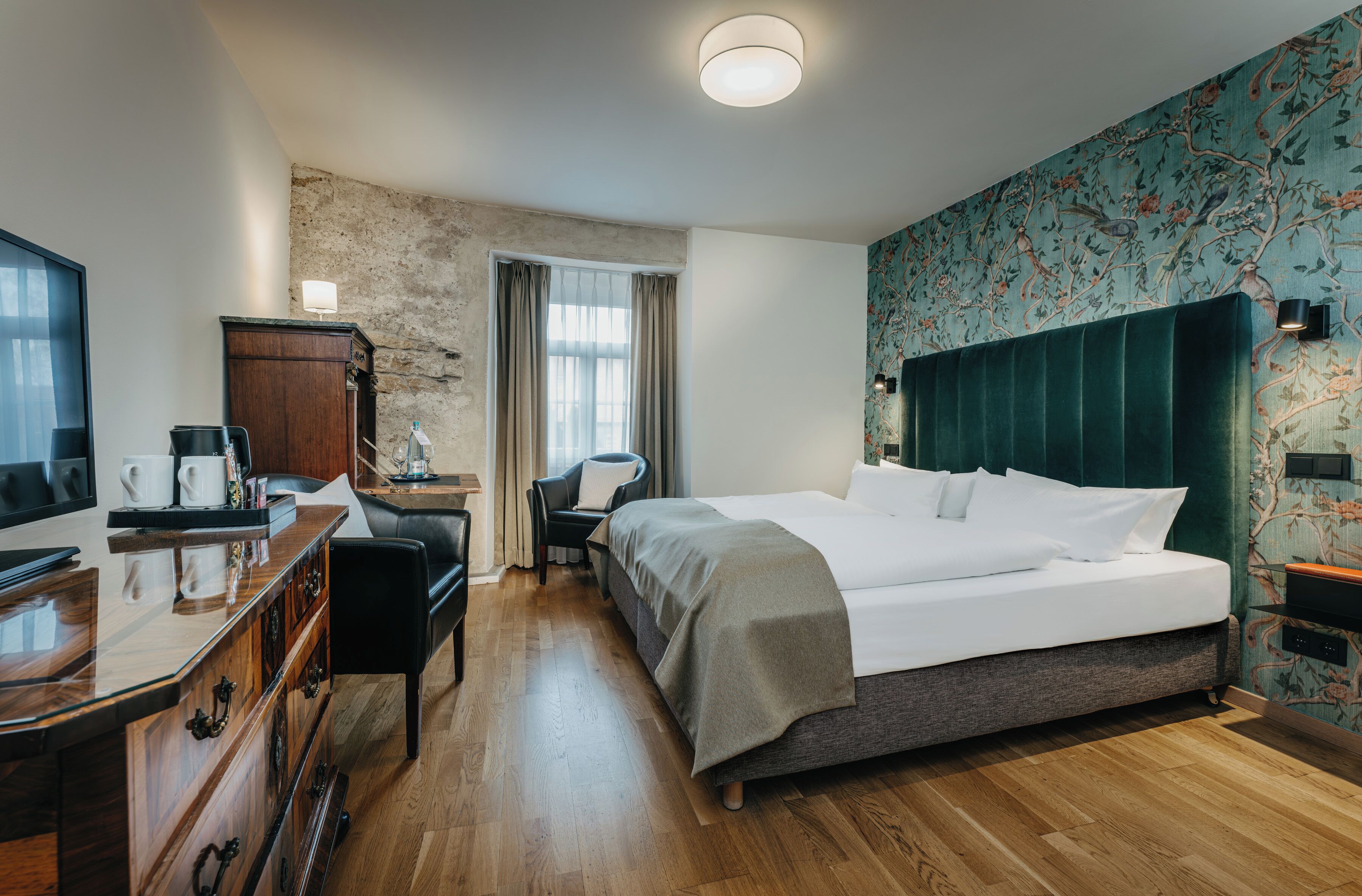 A hotel room with a bed, desk, chair, and wardrobe.