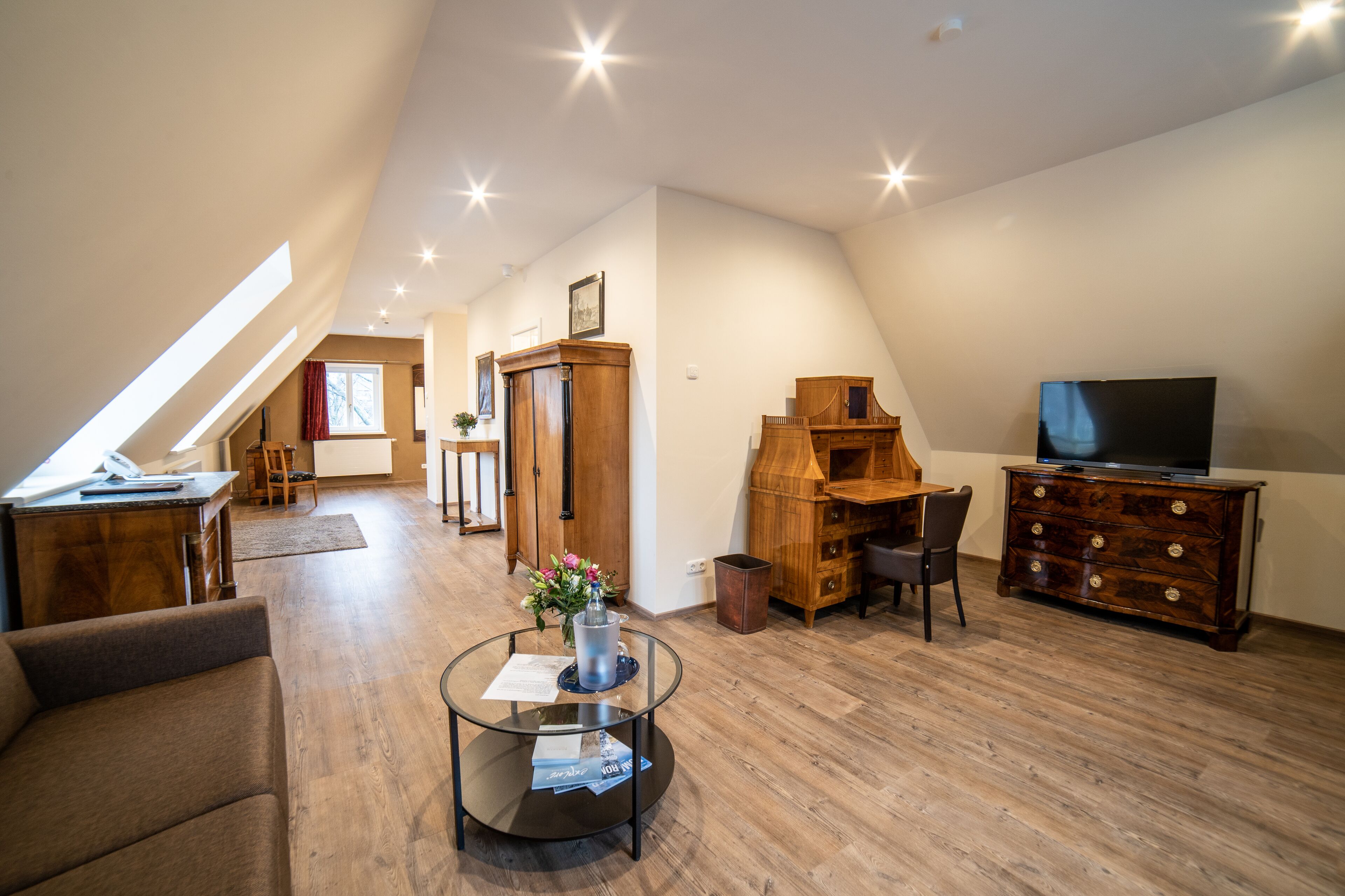 Ein großzügiges Loft mit hohen Decken, Holzböden, einem Essbereich, einem Wohnzimmer mit Fernseher und einem kleinen Balkon.