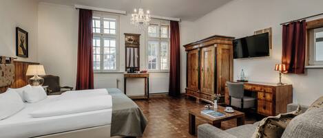 Una habitación de hotel con cama, escritorio, silla, televisión y candelabro.