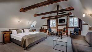 A bedroom with a large bed, a desk, two chairs, and a TV. - Romantik Hotel Alte Münze (Goslar)