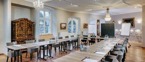 A conference room with long tables, chairs, and a chandelier.