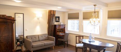 A hotel room with a bed, a sofa, a desk, and a dining table.