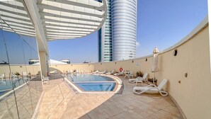 A rooftop pool area with lounge chairs and a swimming pool.