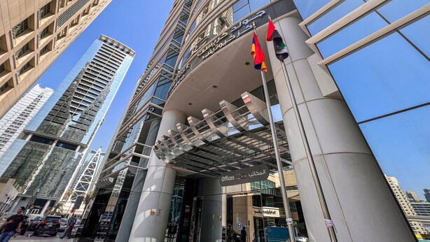 A modern building with a glass facade, multiple floors, and a prominent entrance with a sign indicating it is an office building.