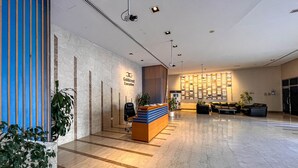 A spacious lobby with a reception desk, seating area, and a wall-mounted display.