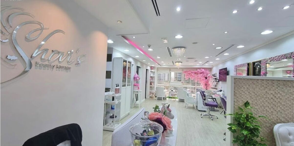 A salon interior with a reception desk, chairs, and shelves with products.