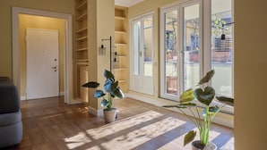 A spacious hallway with wooden flooring, a potted plant, and a sliding glass door leading to an outdoor area. - Milan Retreats Duomo Carrobbio (Milan)
