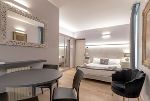 Ein modernes Hotelzimmer mit einem großen Bett, einem runden Esstisch und einem schwarzen Stuhl.