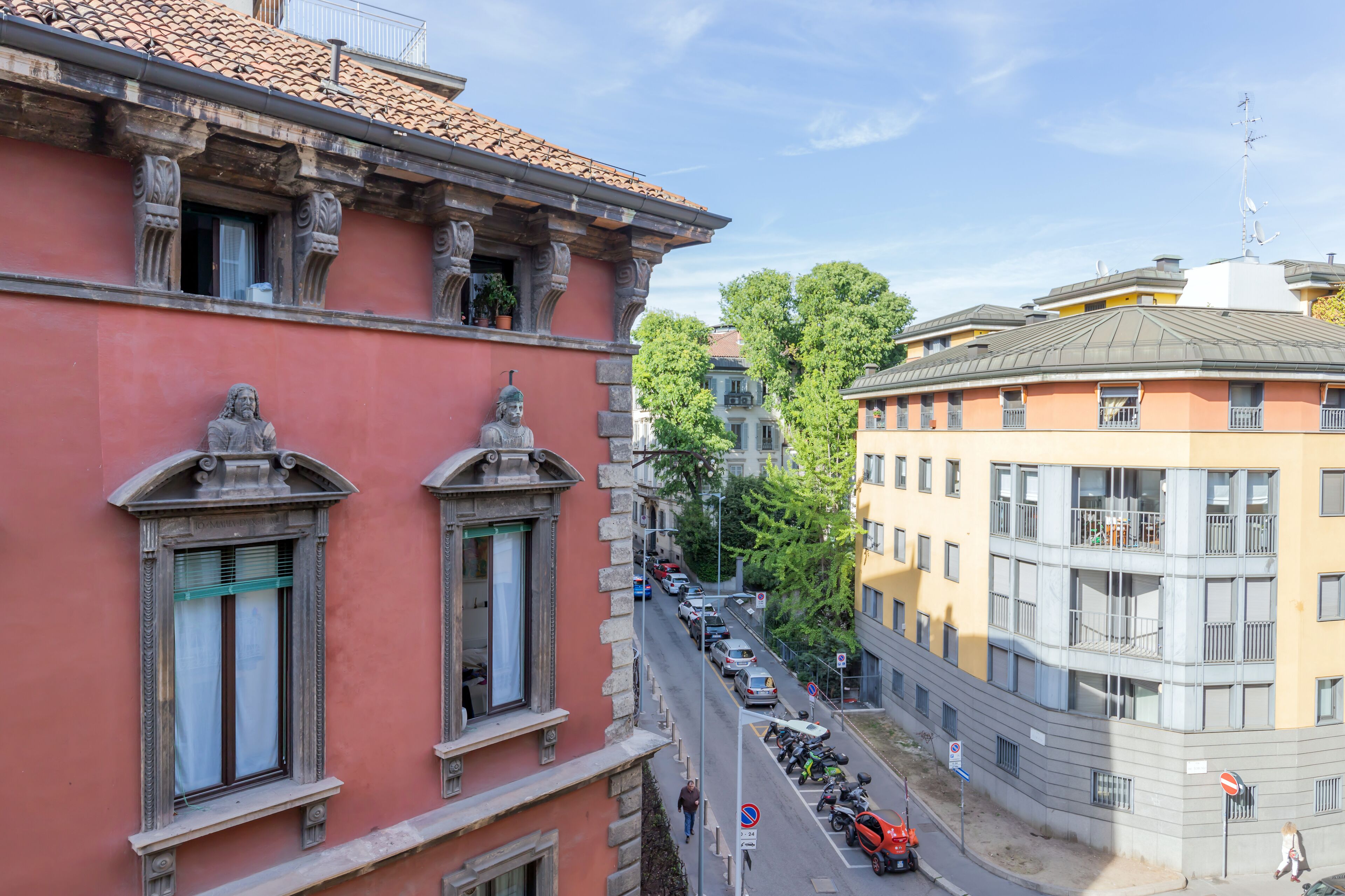 Vista callejera con edificios, cielo despejado y coches estacionados.