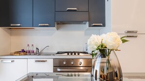 A modern kitchen with stainless steel appliances, a glass countertop, and a vase with flowers on the island. - Milan Retreats Duomo Carrobbio (Milan)
