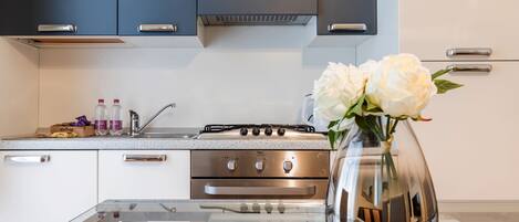 Una cocina moderna con electrodomésticos de acero inoxidable, una encimera de vidrio y un florero con flores en la isla.