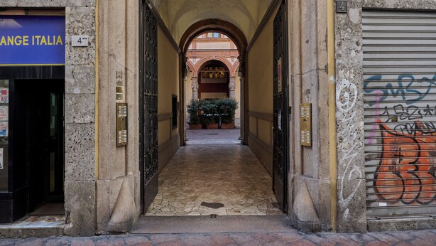 A narrow stone corridor with arched ceilings, leading to a courtyard with potted plants. - Milan Retreats Duomo Carrobbio (Milan)