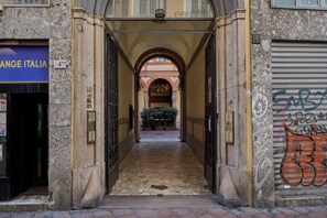A narrow stone corridor with arched ceilings, leading to a courtyard with potted plants. - Milan Retreats Duomo Carrobbio (Milan)
