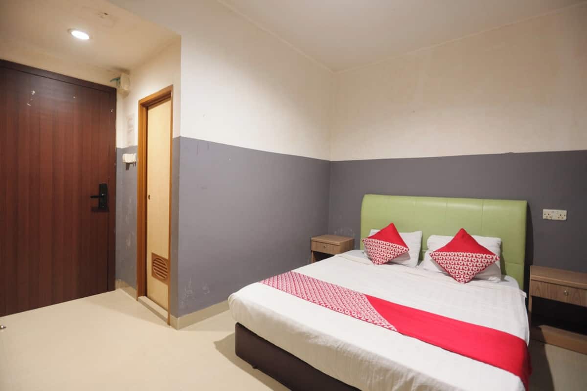 A bedroom with a bed, a wooden wardrobe, a nightstand, and a wall-mounted heater.