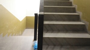 A staircase with a handrail, leading to a landing with a light fixture. - Hotel O City Room (Batam)