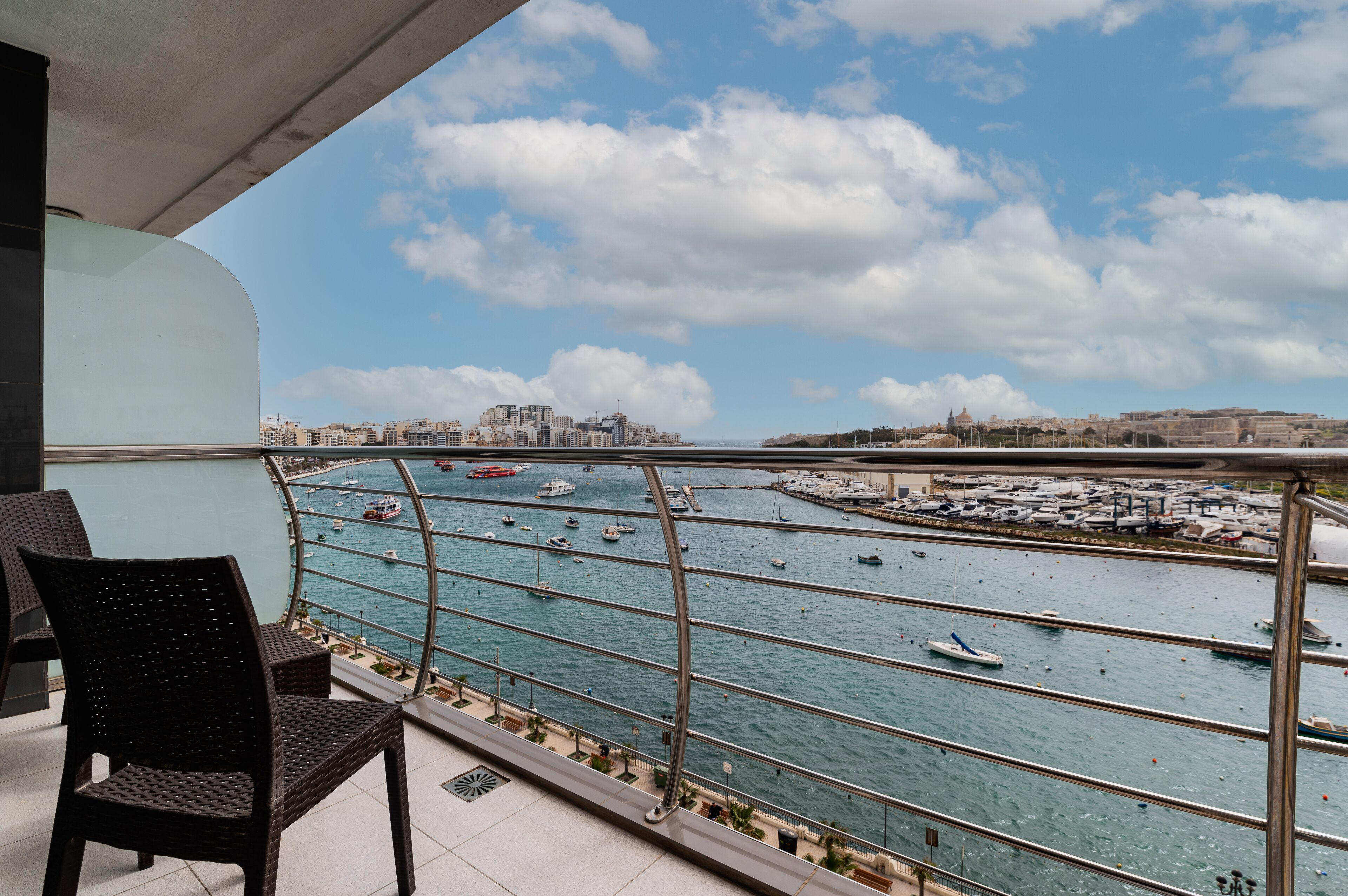 A balcony with a view of a marina and cityscape.