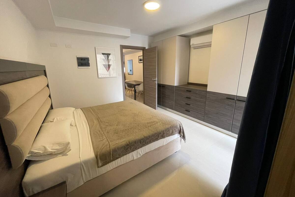 Un dormitorio con cama, armario y espejo.
