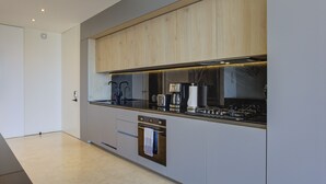 Una cocina moderna con horno empotrado, cafetera y campana extractora de acero inoxidable.
