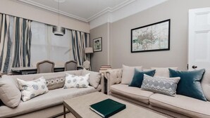 A living room with a beige sofa, a coffee table, and a framed artwork on the wall.
