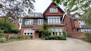 A two-story house with a traditional design, featuring a front entrance, a driveway, and surrounding greenery.