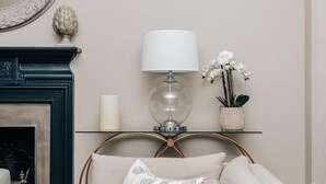 A room with a glass shelf holding a lamp, a candle, and a potted orchid.