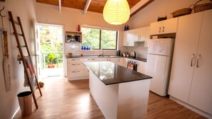 Een moderne keuken met witte kastjes, een centraal eiland en een groot raam dat voor natuurlijk licht zorgt.