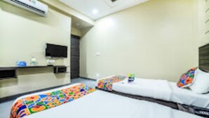 Una habitación de hotel con dos camas, televisión y un minibar.