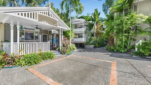 Un hotel con recepción, zona de estar al aire libre y exuberante jardinería tropical.