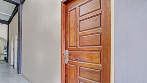 A wooden door with a metal handle and a number "02" on it, leading to a hallway with white tiled flooring and a grey wall. - Hotel O Wisma Pangestu SyariahNearTamanselera (Ujungtanjung)