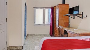 A bedroom with a bed, a desk, a chair, a television, and a window. - Hotel O Wisma Pangestu SyariahNearTamanselera (Ujungtanjung)