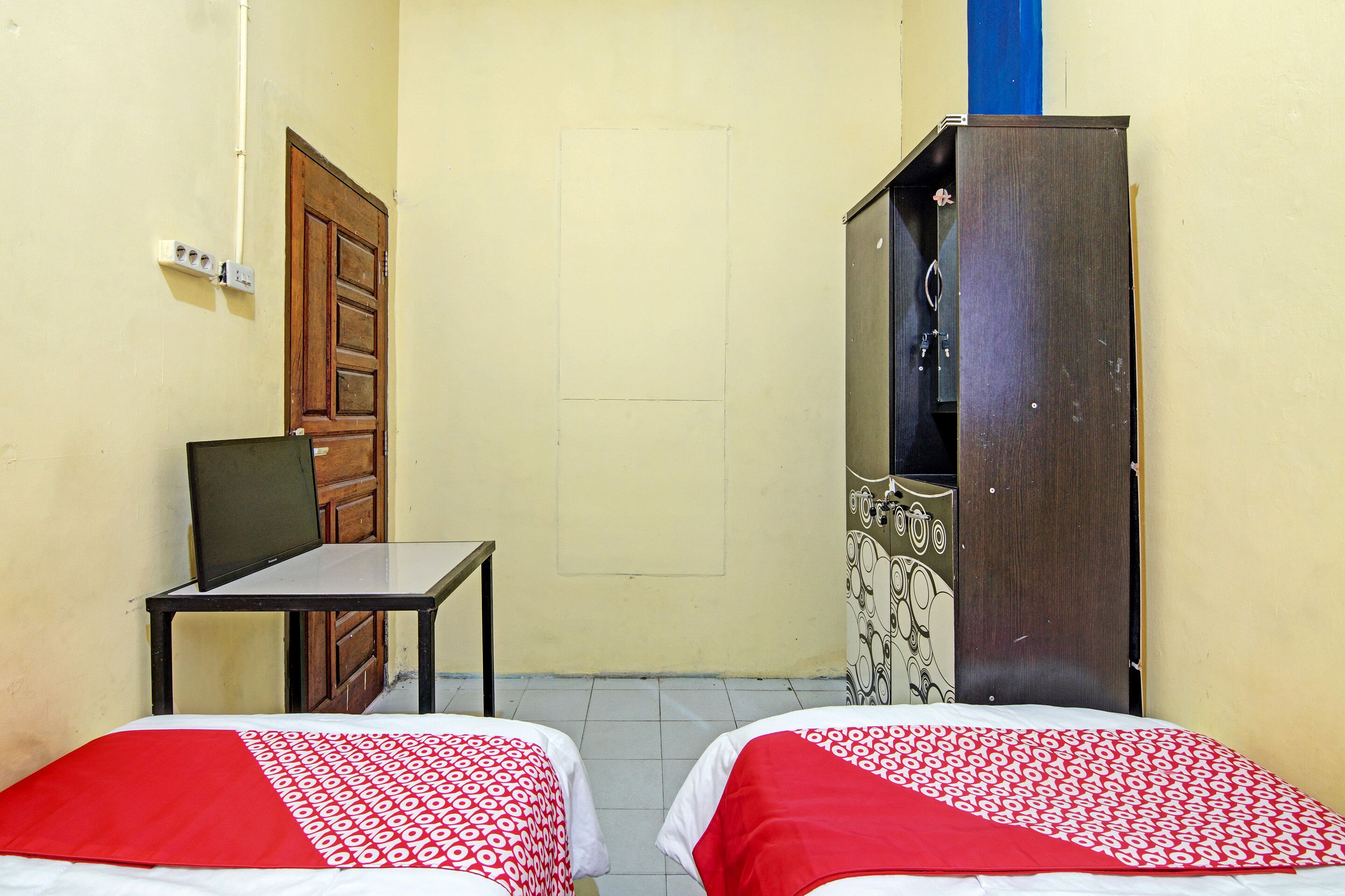 A small room with two beds, a desk, and a wardrobe.