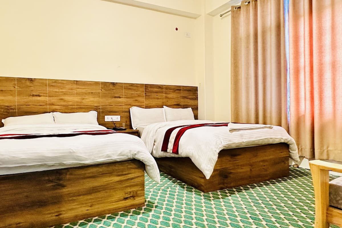 A hotel room with two wooden beds, a green patterned floor, and a wooden headboard.