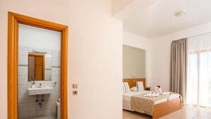 A hotel room with a bathroom, a bed with a headboard, and a large window with curtains. - Ledras Beach Hotel (Rhodes)