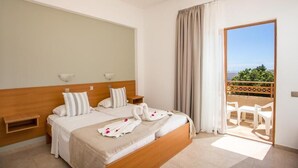 A hotel room with a bed, a nightstand, a wall-mounted lamp, and a balcony with chairs. - Ledras Beach Hotel (Rhodes)