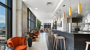 Um lobby de hotel moderno com um extenso balcão, assentos e amplas janelas com vista para a cidade.