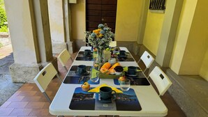 Uma mesa de jantar posta com cadeiras, um vaso com flores e diversos alimentos.