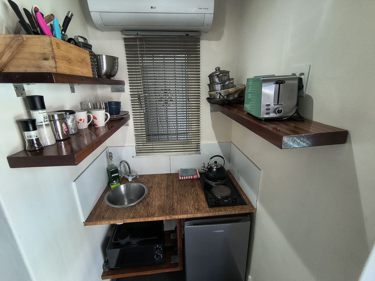 A compact kitchenette with a built-in stove, a sink, and a compact refrigerator.