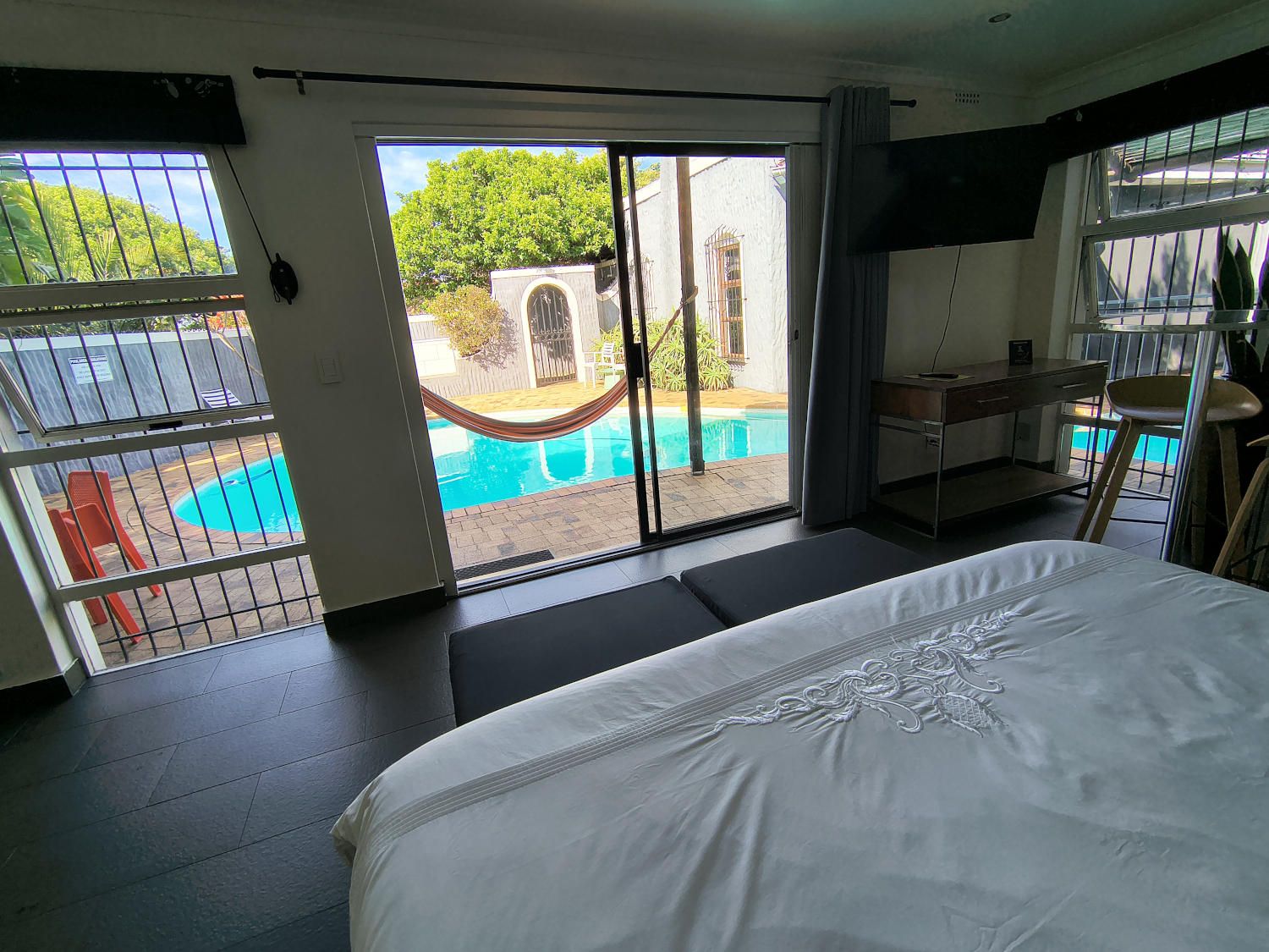 A hotel room with a bed, a desk, a chair, and a view of a swimming pool.