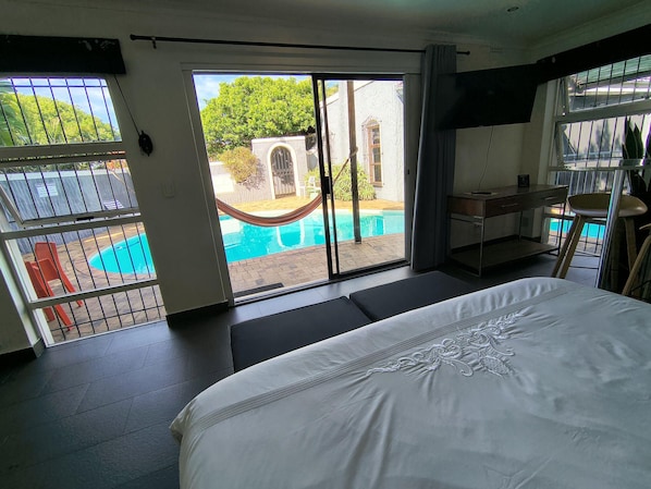 Habitación de hotel con cama, escritorio, silla y vista a una piscina.