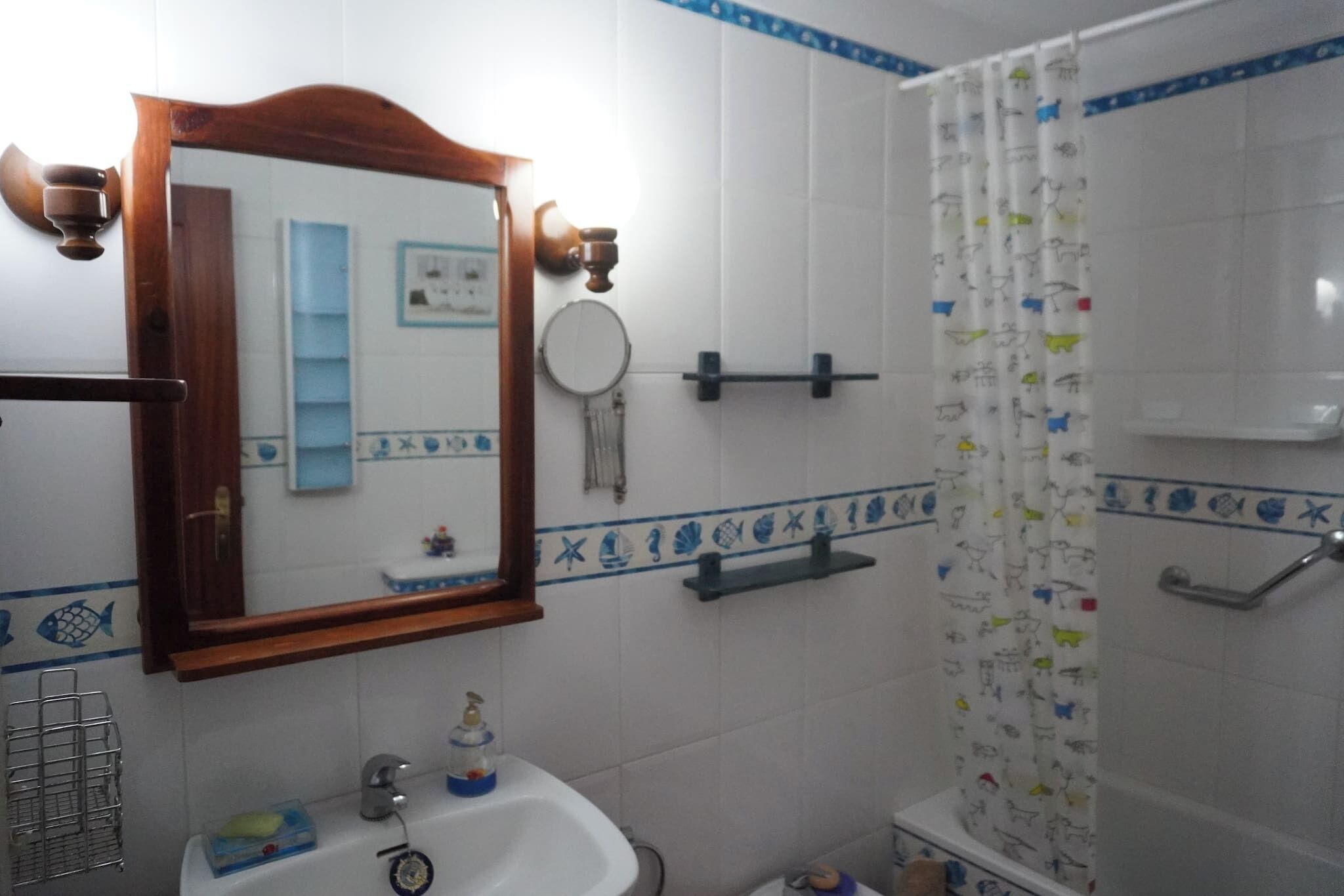 A bathroom with a mirror, sink, and shower curtain.