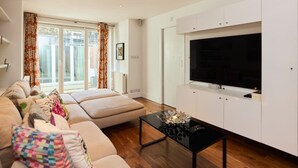 A modern living room with a sofa, a coffee table, and a TV mounted on a white cabinet. - The Clapham Crib (London)