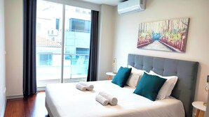 A hotel room with a large bed, a painting on the wall, and a view through the window. - Dorisol IV - Luxury Apartment in La Vie (Funchal)